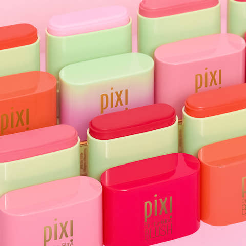 A close-up arrangement of Pixi Glow blush tubes in multiple pastel and bright shades, including pink, mint green, coral, and red, with gold 'pixi' branding visible on the tubes.