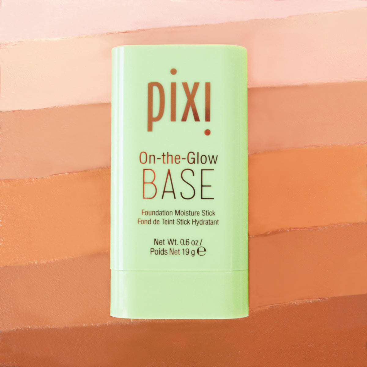 Pixi On-the-Glow Base Foundation Moisture Stick in a light green container, set against a background of horizontal peach and orange color swatches.