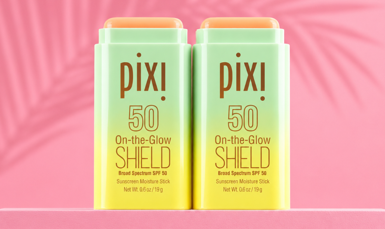 Two Pixi On-the-Glow Shield SPF 50 sunscreen sticks on a pink background with palm shadow