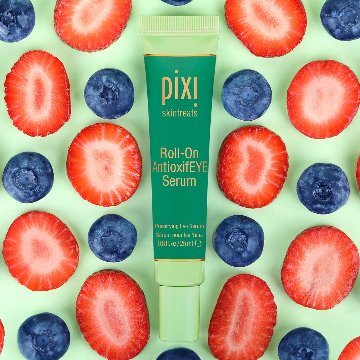 PIXI Roll-On AntioxidEYE Serum surrounded by sliced strawberries and blueberries on a green background